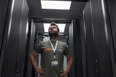 Erkek teknisyen ya da ağ yöneticisi portresi veri merkezi sunucu odasında kolları çaprazlanmış kahraman gibi duruyor. Yüksek kalite fotoğraf