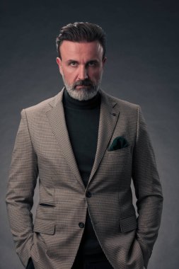 Fotoğraf stüdyosunda sakallı ve sıradan iş kıyafetleri giyen zarif bir kıdemli işadamının portresi. Koyu renk arka planda el kol hareketleriyle izole edilmiş. Yüksek kalite fotoğraf