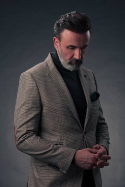 Fotoğraf stüdyosunda sakallı ve sıradan iş kıyafetleri giyen zarif bir kıdemli işadamının portresi. Koyu renk arka planda el kol hareketleriyle izole edilmiş. Yüksek kalite fotoğraf