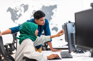 Çok ırklı girişimci Arap kadın takımı modern açık planlı ofis iç mimarisinde buluşmaya tesettüre girmiş, dizüstü bilgisayar ve bilgisayar üzerinde çalışıyor. Seçici odaklanma. Yüksek kalite