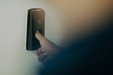 Alarm sisteminde parmak izi tarayıcısına basan adam, kapının kilidini açmak için parmak izi taraması yapıyor. Yüksek kaliteli fotoğraf.