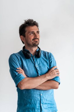 Resmi bir erkek portresi. Kendine güvenen başarılı bir iş adamı ya da yönetici beyaz bir arkaplan önünde duruyor, kollarını kavuşturup doğrudan kameraya bakıyor ve dostça gülümsüyor. Yüksek