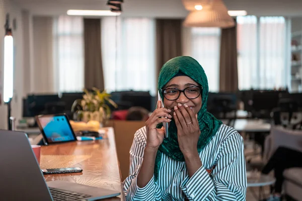Gülümseyen Genç Bir Kadın Akıllı Telefonda Konuşur Dizüstü Bilgisayarda Çalışır — Stok fotoğraf