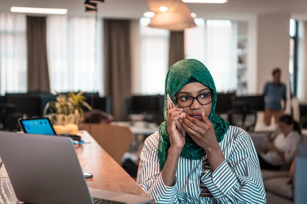Gülümseyen Genç Bir Kadın Akıllı Telefonda Konuşur Dizüstü Bilgisayarda Çalışır — Stok fotoğraf