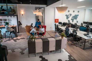 Modern açık planlama ofisindeki rahatlama alanının tadını çıkarırken farklı şeyler yaparak işten izin alan çok ırklı iş adamlarından oluşan bir grup. Yüksek kalite fotoğraf
