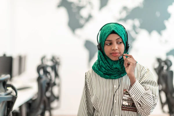 带着绿色头巾的非洲穆斯林女性客户代表女商人带着手机耳机在线帮助和支持一位现代呼叫中心的客户 高质量的照片 — 图库照片