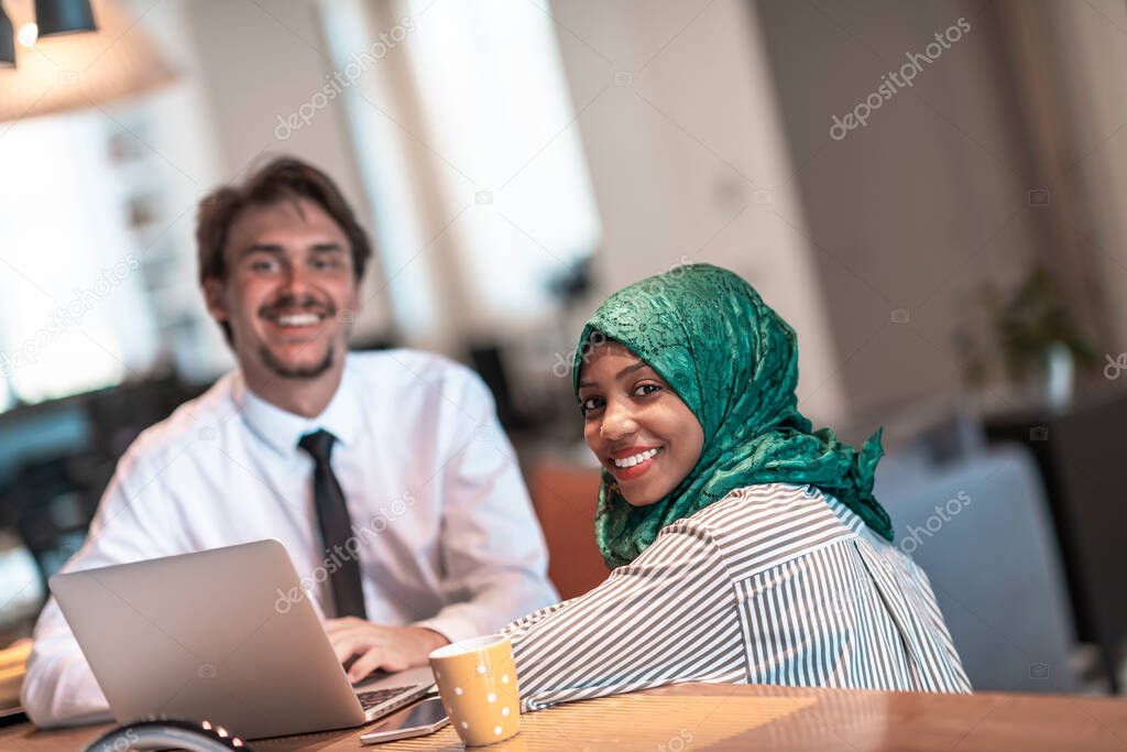 International multicultural business team.Man and Muslim woman with hijab working together using smartphone and laptop location area at modern open plan startup office puter in real. High-quality