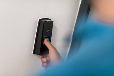 Alarm sisteminde parmak izi tarayıcısına basan adam, kapının kilidini açmak için parmak izi taraması yapıyor. Yüksek kaliteli fotoğraf.