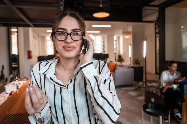 Modern açılış planlama ofis içinde akıllı telefon kullanan gözlüklü bir iş kadını. Seçici odaklanma. Yüksek kaliteli fotoğraf.