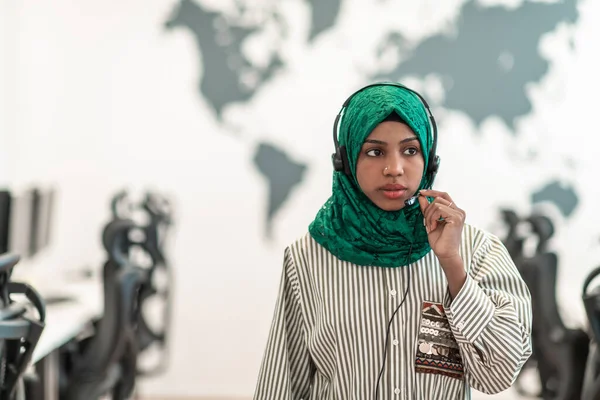 Afro Muslim fêmea com hijab verde cachecol representante do cliente mulher de negócios com fone de ouvido de telefone ajudando e apoiando on-line com o cliente no moderno call center — Fotografia de Stock