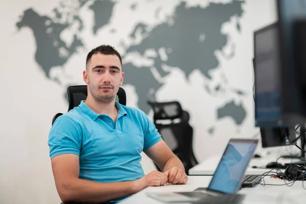 Junger Mann sitzt im Büro und arbeitet am Desktop-PC. Geschäftsmann schaut im Büro auf Computermonitor. — Stockfoto
