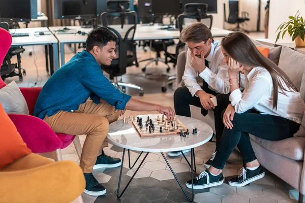 Multiethnische Gruppe von Geschäftsleuten, die Schach spielen, während sie im Ruhebereich eines modernen Startup-Büros eine Pause einlegen — Stockfoto