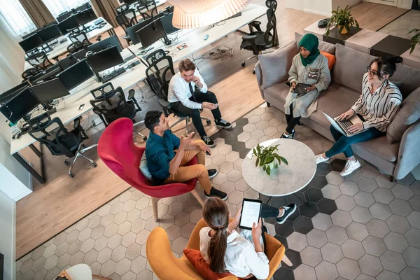 Top view photo of Multiethnic startup business team having brainstorming in relaxation area of modern office interior working on laptop and tablet computer — Stock Photo, Image