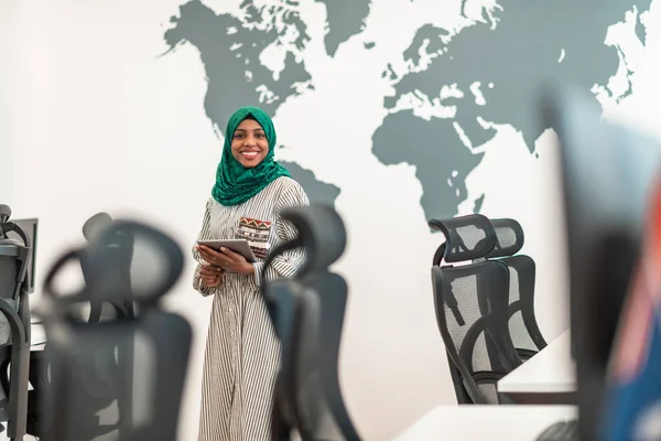 Porträtt av muslimsk kvinnlig mjukvaruutvecklare med grön hijab innehav tablett dator när du står vid modern öppen planlösning start kontor — Stockfoto