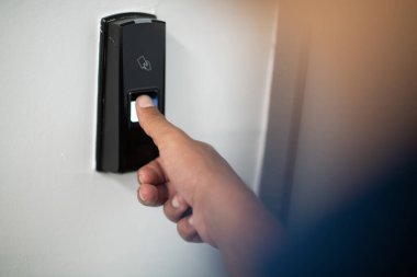 Alarm sisteminde parmak izi tarayıcısına basan adam kapının kilidini açmak için parmak izi taraması yapıyor.