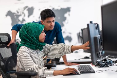 Çok ırklı girişimci bir iş kadını modern açık ofis ofis iç mimarisi buluşmasında tesettür takıyor, dizüstü bilgisayar ve dizüstü bilgisayar üzerinde çalışıyor. Seçici odak 