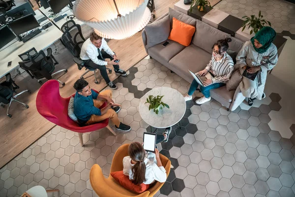 Top view photo of Multiethnic startup business team having brainstorming in relaxation area of modern office interior working on laptop and tablet computer — Stock Fotó