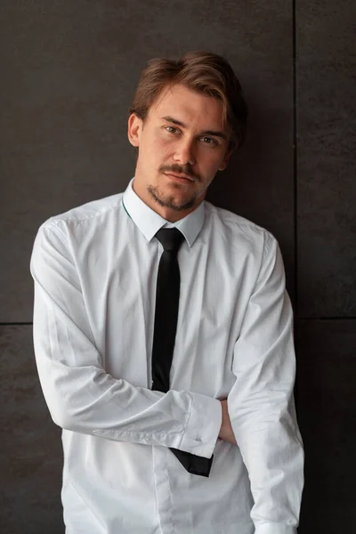 Portré startup üzletemberről fehér ingben, fekete nyakkendővel a szürke fal előtt. — Stock Fotó