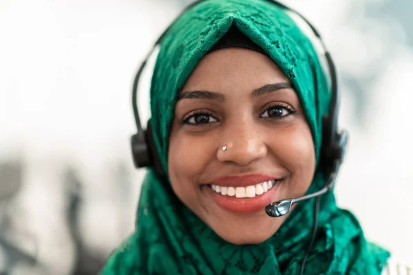 Mujer musulmana con bufanda verde hijab representante de los clientes mujer de negocios con auriculares telefónicos ayudando y apoyando en línea con el cliente en el centro de llamadas moderno — Foto de Stock