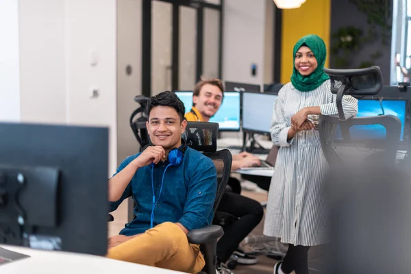 Πολυεθνική startup επιχειρηματική ομάδα Αραβική γυναίκα φορώντας μια μαντίλα στη συνάντηση στο σύγχρονο ανοιχτό σχέδιο γραφείο εσωτερικό brainstorming, εργάζονται σε φορητό υπολογιστή και επιτραπέζιο υπολογιστή. Επιλεκτική εστίαση — Φωτογραφία Αρχείου