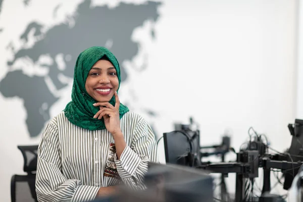 Retrato de desenvolvedor de software feminino preto muçulmano com hijab verde em pé no escritório de inicialização em plano aberto moderno. Foco seletivo — Fotografia de Stock