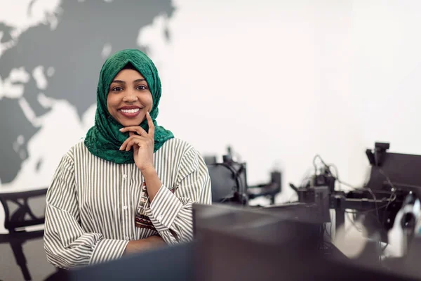 Retrato de desenvolvedor de software feminino preto muçulmano com hijab verde em pé no escritório de inicialização em plano aberto moderno. Foco seletivo — Fotografia de Stock