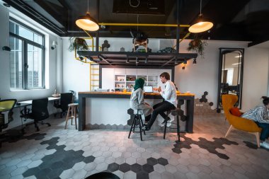 Bir grup çok ırklı iş adamı, modern açık planlama ofisindeki dinlenme alanının tadını çıkarırken farklı şeyler yaparak işe ara veriyor. Yüksek kaliteli fotoğraf.