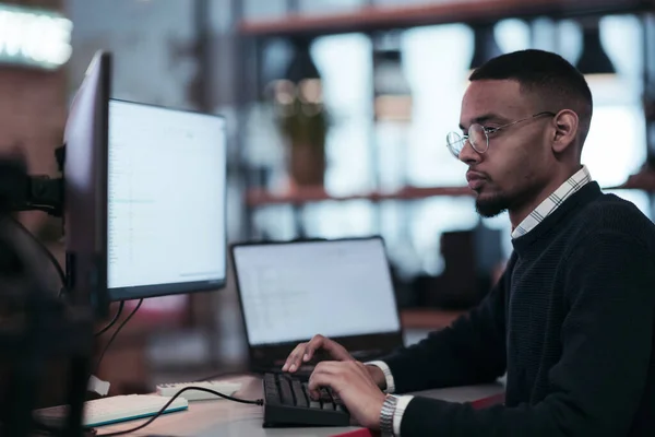 Gözlüklü genç Afrikalı Amerikalı modern bir ofiste oturuyor ve bilgisayar başında çalışıyor. — Stok fotoğraf