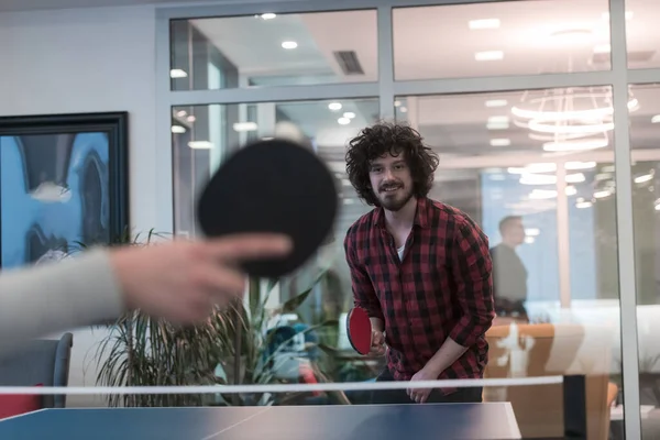 Dva mladí začínající podnikatel hrát ping pong tenis na moderní tvůrčí kancelářské prostory lidé skupina mají setkání a brainstorming v pozadí — Stock fotografie