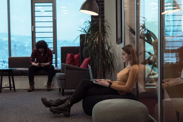 Dos mujeres de negocios situadas en un moderno espacio de coworking en un descanso del trabajo y relajarse con un ordenador portátil. Enfoque selectivo —  Fotos de Stock