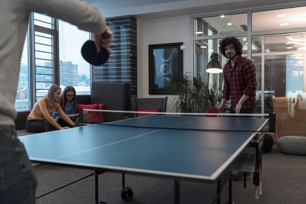 Két fiatal start up üzletember ping-pong teniszezik a modern kreatív irodahelyiségben emberek csoportjának találkozója és ötletelése a háttérben — Stock Fotó