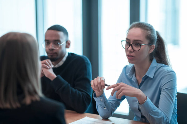 Successful team. Group of young multi-ethnic business people working and communicating together in creative office. Selective focus 