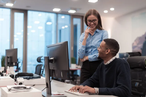 Junge lächelnde Frau erklärt ernsthaften afroamerikanischen Mitarbeitern die Projektstrategie. Diverse Start-up-Mitarbeiter Studenten und Männer diskutieren über das Arbeiten im modernen Büro mit dem Computer. — Stockfoto