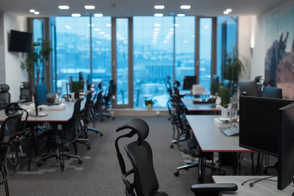 Vista frontal del interior de la oficina de coworking con lugares de trabajo, marco de imagen en blanco en la pared y el ordenador. — Foto de Stock