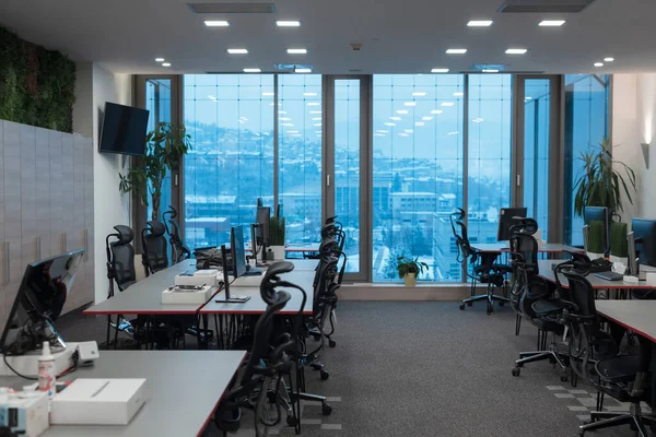 Vista frontal do interior do escritório de co-trabalho com locais de trabalho, moldura em branco na parede e no computador. — Fotografia de Stock