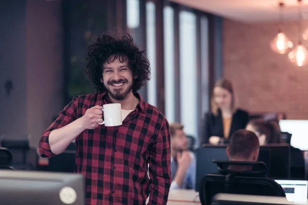 Lächelnder Geschäftsmann im Afrohemd, der mit einer Tasse Kaffee in der Hand im modernen Büro steht. Selektiver Fokus — Stockfoto