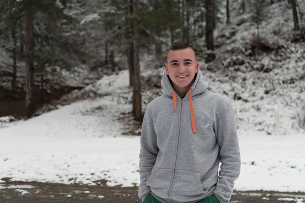 Portret młodego mężczyzny w śnieżnym lesie ubranego w luźne ubrania. Skupienie selektywne — Zdjęcie stockowe