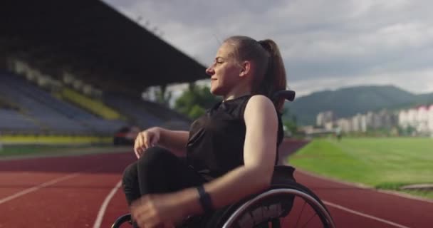 Una mujer con discapacidad calentándose en silla de ruedas en pista de atletismo — Vídeos de Stock