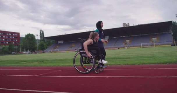 Tekerlekli sandalyeye mahkum bir kadın atletizm antrenmanında tesettürlü Müslüman bir kadınla. — Stok video