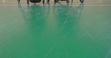 Tekerlekli sandalyeli iki arkadaş modern bir salonda maçın başlamasını bekliyorlar.