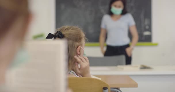 Nauczyciel namawiający ucznia, by założył mu maskę na twarz. Lekcje podczas pandemii w szkole. — Wideo stockowe