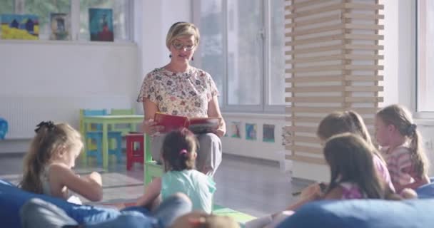Вчитель читає книгу дітям у початковій школі — стокове відео