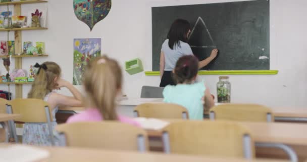 Learning process at school, female teacher writes with chalk on the chalkboard. — Stockvideo