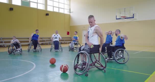 Persoanele cu dizabilități se întind înainte de un joc de baschet în sala modernă. Slow motion — Videoclip de stoc