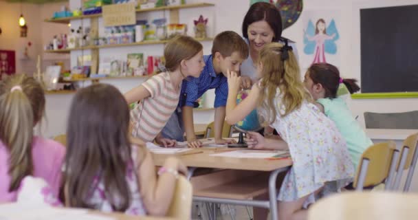 Učitelka s dětmi na hodině zeměpisu, dívající se na zeměkouli. Boční pohled na skupinu různorodých šťastných školáků s glóbus ve třídě ve škole. — Stock video