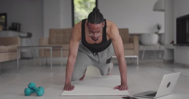 Підійде афро-американський спортсмен, який дивиться онлайн-тренувальні заняття на ноутбуці, повторює ходи після інструктора, відпрацьовує вправи для ніг вдома. Самоізоляція. карантину . — стокове відео