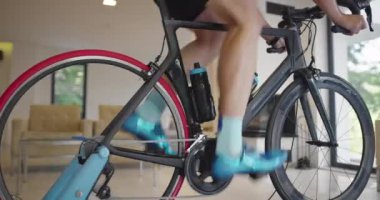 Bisikletli bir adam evde egzersiz yapıyor. Coronavirus Covid19 tecridi sırasında çevrimiçi bisiklet yarışı oynuyor. Yeni normal kavram.