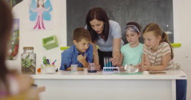 İlköğretim Okulu Bilim Sınıfı: Coşkulu Öğretmen Kimyayı Çeşitli Çocuklar Grubu 'na Açıkladı, Küçük Çocuk Kimyasalları Beakers' a Karıştırdı. Çocuklar Faiziyle Öğrenin