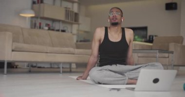 Coronavirus salgını sırasında müşteriyle çevrimiçi eğitim için dizüstü bilgisayar kullanan Afrikalı Amerikalı fitness eğitmeni.