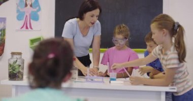 İlköğretim Okulu Bilim Sınıfı: Coşkulu Öğretmen Kimyayı Çeşitli Çocuklar Grubu 'na Açıkladı, Küçük Çocuk Kimyasalları Beakers' a Karıştırdı. Çocuklar Faiziyle Öğrenin